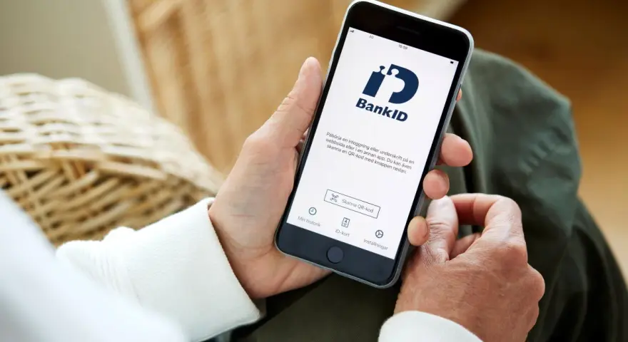 Person använder sin smartphone med BankID-appen för att logga in eller signera.