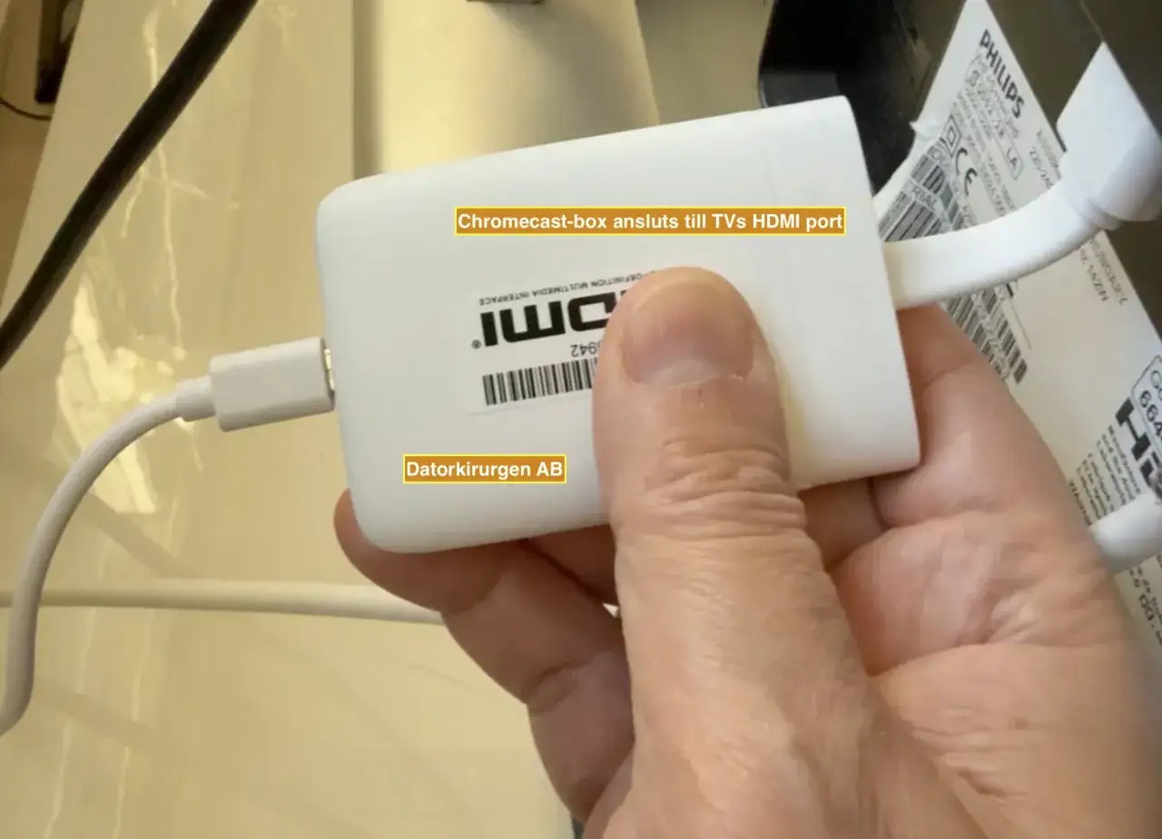 En hand håller en vit Chromecast-box ansluten till en TV, redo för iptv Tele2.