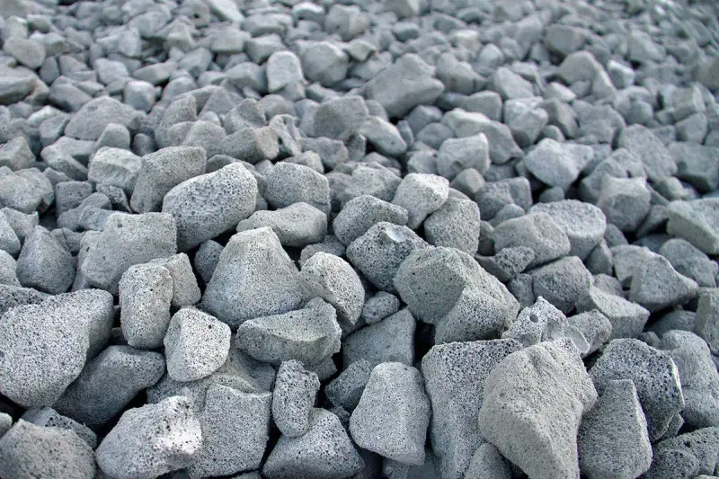 En stor hög med grå, porösa stenar. Skumglas nackdelar kan vara att materialet är lätt och kan blåsa iväg.